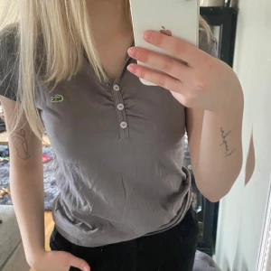 Lacoste T-shirt 🐊 - Beige/grå T-shirt med knappar i mitten. Har knappt blivit använd. Skicka för fler bilder eller bild på!🩷
