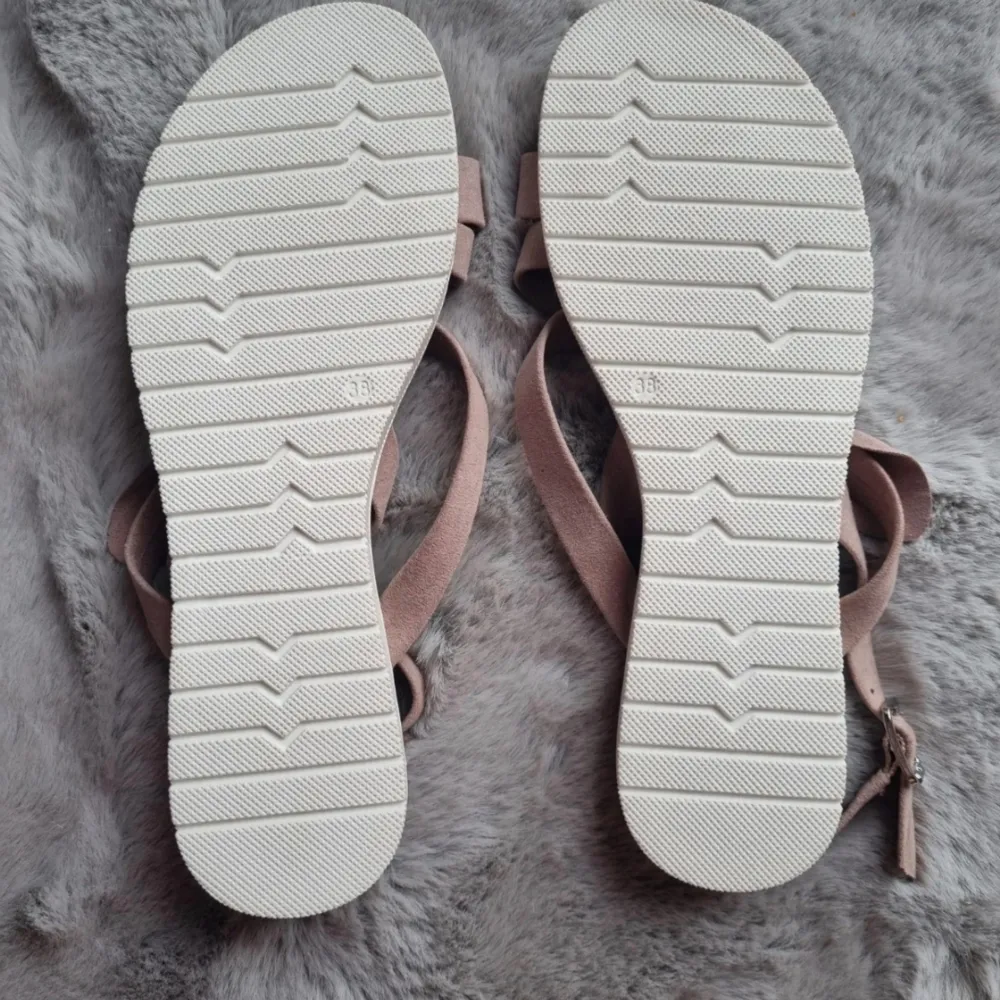 Beige/rosa sandaler med rosett, justerbar vristrem. Storlek 38, bedömmer som normal. Innermått ca 24 cm, fotblad ca 8,5 cm, sula fram ca 1 cm och klack ca 2 cm. Oanvända.. Skor.