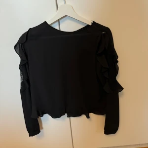 Blus från Zara - Gin blus från Zara med spets på båda ärmarna och fina volanger. Knäppning i ryggen hela vägen. Knappt använd. 