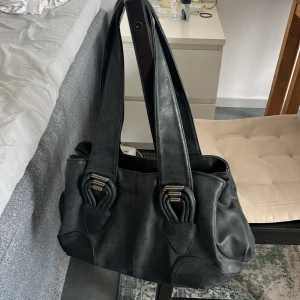 Vintage moonchilli väska - Grå väska i något slags skinnmaterial. Jättebra skick, som oanvänd, trots att den är vintage. Kommer inte till användning därav säljer jag den🤍