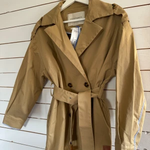 Scotch & Soda Trenchcoat Dam - En helt ny och superfin trenchcoat i färgen: camel/beige. Storleken är Small men upplever den som rymlig i modellen. Frakt tillkommer.