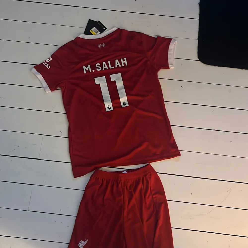 Säljer min lillebrorsas gamla Mohammed Salah Liverpool kit då han vuxit ur den. Skick 9/10 knappt använd. Shorts ingår.. Sport & träning.