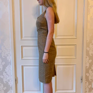 Guldig klänning, Emmy design  - Jättefin  guldig klänning i skönt material. Storlek 42.  Modellen har samma klänning S38 Modellen på bilden är 173 cm och har storlek 38 i de flesta andra kläder. Aldrig använd. Vi har lagt ner vår klänningsbutik och säljer ut. Ny pris är 2000-3000kr