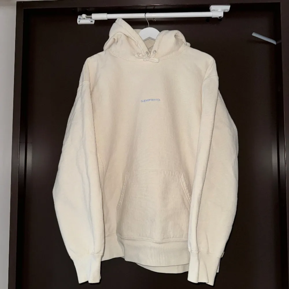 Supreme hoodie jag knappt använt.  Bra skick. Storlek L, jag är 180cm 73kg. Den är krämvit med blå supreme brodering.  Väldigt bra kvalite på tröjan, den är tung och tjock i tyget så den sitter väldigt snyggt.  Number one hooded sweatshirt FW21. Hoodies.