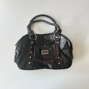 Brun handväska - Brun oanvänd vintage handväska i skinnimitation och guld detaljer. Bredd: ca 30 cm. Djup: 12 cm. Höjd: 21 cm 💕