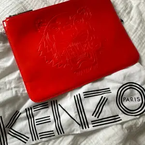 Aldrig använd clutch från Kenzo med tillhörande dustbag💕Köpt för några år sedan men i nyskick. Färgen är lite svår att fånga på bild men man ser böst på sista bilden!!