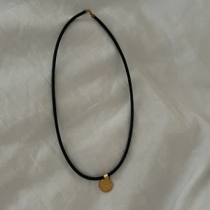 Halsband lira  - Lira halsband i guld med svart kedja. 585 stämpel, 14k guld.