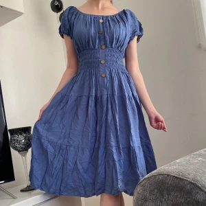 Blå bomullsklänning - Blå sommarklänning i skrynkligt bomull. Använd en sommar. Kan bäras som kortärmad eller off shoulder. Resår i midjan gör att den passar XS-M. 