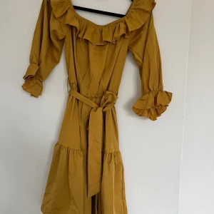 Klänning  - Här har vi en vacker och unik klänning till både festligheter och vardagslivet. Har en lite Touch av champagne färg och guld.  Ett band runt som du kan knyta hårt om du vill att det ska sitta lite tightare. Fin modell vid axlarna och armarna. 