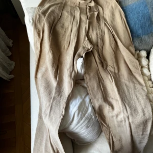 Oanvända - Högmidjade byxor från H&M - Snygga byxor till sommaren tillsammans med en vit skjorta och sandaler. Är väldigt höga i midjan men med vidare ben, väldigt luftiga. Är lagom i benen på mig som är 160 cm, annars är de croppade.  Storlek 34