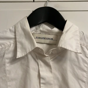 Skjorta med unika detaljer  - Snygg längre skjorta i oversize modell från Marlene Birger. I designen något längre bak än fram. Ska egentligen sitta en pärla vid armsluten som lossnat så knutit dem med en tråd ☺️Använt skick. Nypris ca 1800kr. Passar en 36/38