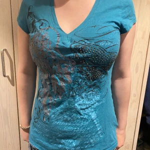 Guess t-shirt - Säljer denna jättefina Guess tröjan. Säljer eftersom att det inte är min smak längre. Köpt second hand så inte alla ”kristaller” är på. Använd men i okej skick.