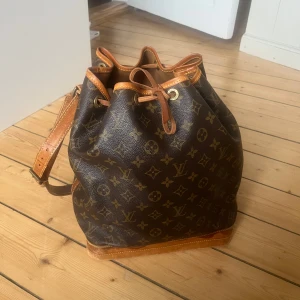 Louis Vuitton Noé - Louis Vuitton Noe Bag köptes från en autentisk säljare på Vestiaire Collective för 2 år sedan. Axelremmen har lossnat på ena sidan men går enkelt att laga hos skomakare. Fläckar på lädret, insidan av väskan är ren, skriv för fler bilder!