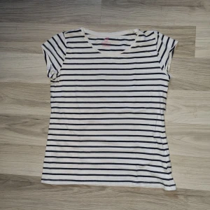 Vit och svart randig t-shirt - En vit och svart randig t-shirt med korta ärmar. T-shirten har en rund halsringning och är i normal passform. Från H&M i stl 146/152