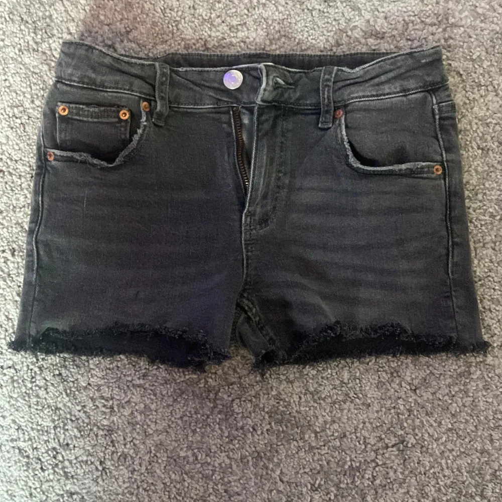 Ett par svarta jeansshorts från Gina Tricot i storlek 152. Shortsen har en rå kant vid bensluten och klassisk femficksdesign med knapp och dragkedja framtill.. Shorts.