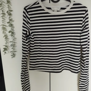 Randig Tröja  - Svart vit, randig långärmad basic tröja för kvinnor. Den har en kort stil, så den slutar vid nedre magen. Storlek: S. Kommer från H&M. Använd ett få antal gånger, i bra skick. Bomullstyg. 