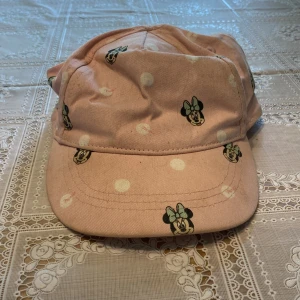 Mimmi-keps - Söt mimmikeps i färgen ljusrosa. Har små prickar och motiv av mimmi. Är i storleken 92/104 & är från H&M. Änvänd ganska många gånger.