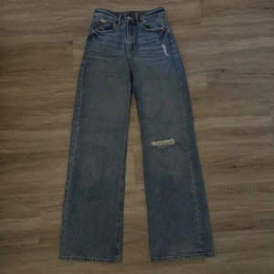 Blå Jeansbyxa  - Ljus blå Jeansbyxa från H&M med slits på ena knät. Storlek 36. Hög midjade 