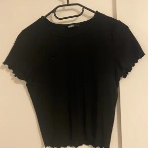 T-shirt  - Svart ribbad T-shirt. Använd mycket är smått noppriga 