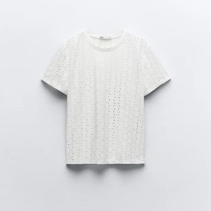 Vit t-shirt med hålmönster - En vit t-shirt från Zara med ett dekorativt hålmönster. T-shirten har korta ärmar och en rund halsringning.