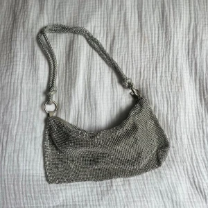 Glittrig silvrig väska - Så snygg väska. Tyvärr har en sten lossnat, se bild 3