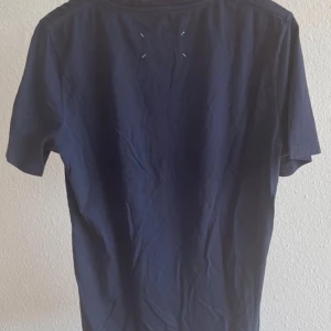 Maison Margiela t-shirt - Maison Margiela tisha i marinblå färg med ett litet tryck (står under maison margiela på trycket). Lite sällsynt men många har den fortf. Skick 8/10. Skriv om funderingar🙌