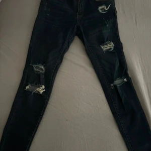 Svarta jeansbyxor från Club XPRS - Ett par  jeansbyxor från Club XPRS med slitna detaljer. Byxorna har en klassisk femficksdesign och är tillverkade i ett slitstarkt material.