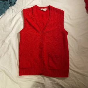 Röd stickad väst - En vintage stickad röd väst, köpt secondhand i mkt bra kvalitet. Tror den är gjord av ull. Stl 44 på lappen men passar snarare som en M