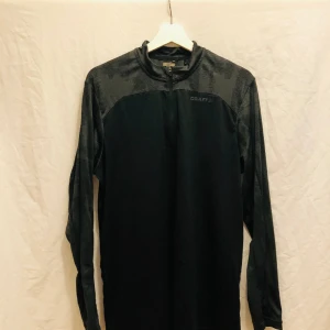 Craft halfzip träningströja  - Behaglig träningströja med luft återcirkulerande material. Nyskick, inga defekter. Svart & grå. Finns även i militärgrön& grå.