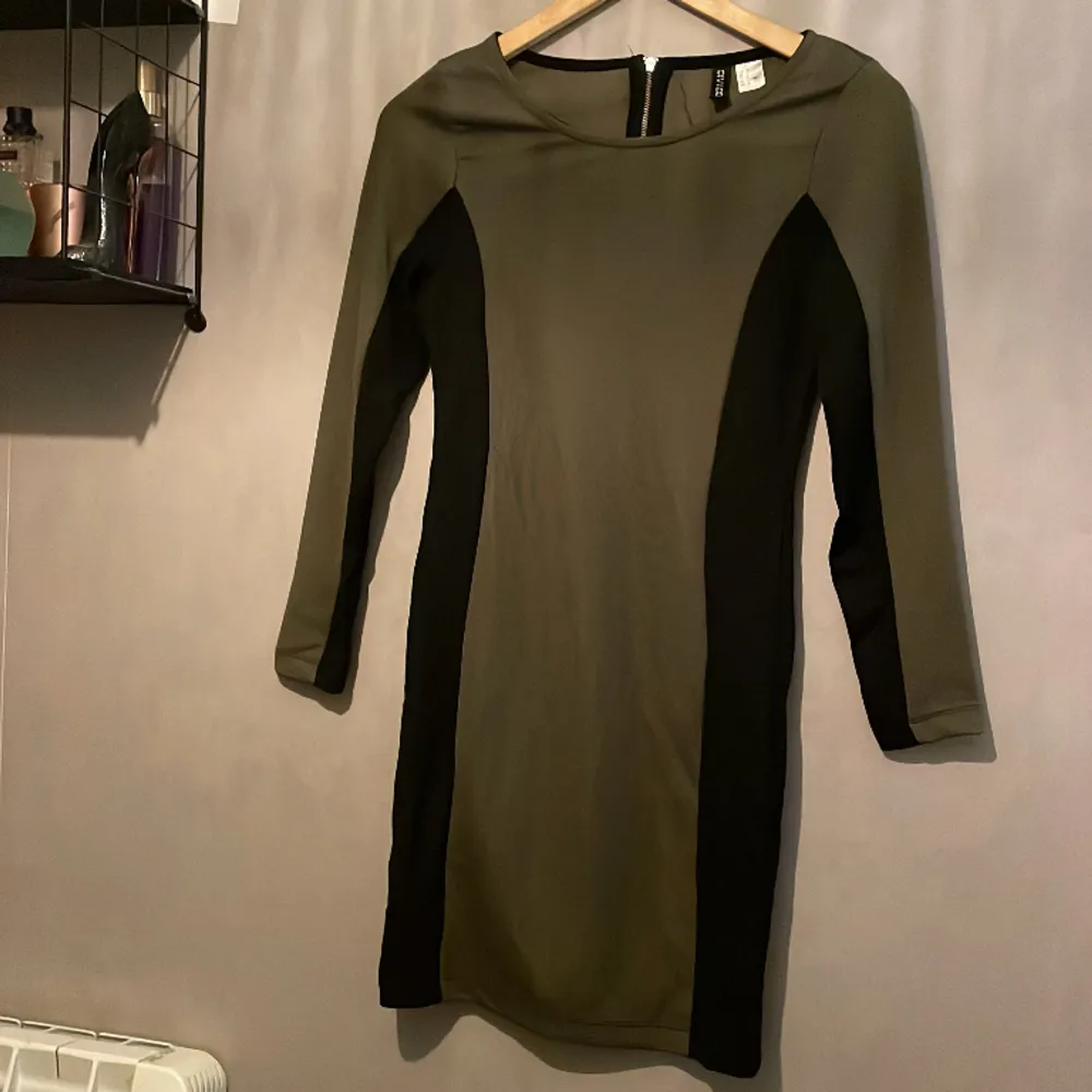Säljer denna klänning från H&M, storlek 38 men passar även som 36 då den är ganska tajt. Klänningen är olivgrön med svart på kanterna. Klänningar.