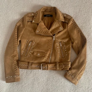 ZARA brun mockajacka med utsmyckning - SÅ fin mockajacka från ZARA. Aldrig använd, utan anmärkningar. Väldigt mjuk mockaimitation utsmyckad med diamantstenar, pärlor och stygn med silverglittriga trådar.