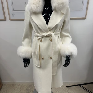 Veronica coat off-white - En lång vit kappa med guldiga knappar och äkta avtagbar päls. Helt ny och oanvänd (bara på bild)  storlek S och jag är 170cm. Ord pris 2999kr 