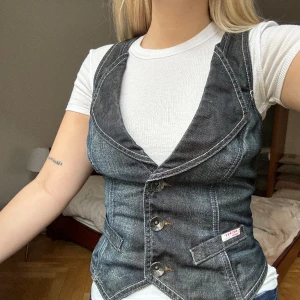 Denim väst - Säljer denna snygga väst i mörk denim köpt vintage. På märket står det ”ICHI”. I bra skick, säljer på grund av att den inte kommer till användning. 