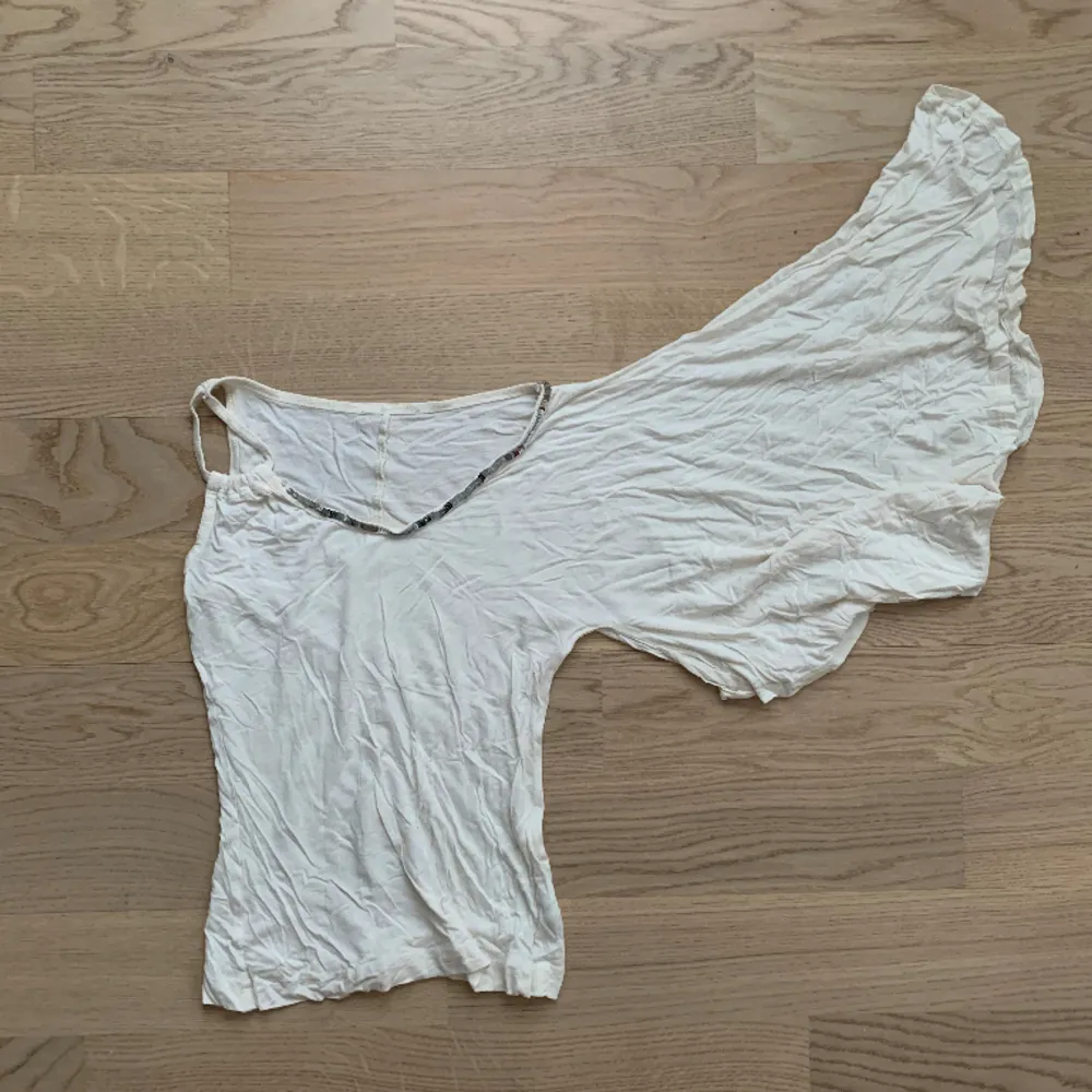 Vit partytopp med en arm. Den har Ă€ven paljetter vid kragen đ storlek XS/S. Puserot.