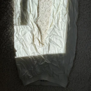 Vita byxor  - Byxor från Djerf Avenue, dem sitter väldigt rakt i passformen så dem är inte så pösiga, dem är glansiga i materialet och materialet skulle jag säga är silke