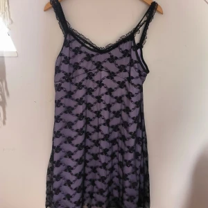 Lila Svart Spets klänning  - Lila och Svart Spets klänning med dubbel band och liten rosett. Aldrig använt och kan stretchas ut lite.