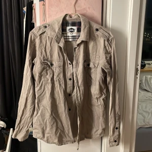 Tröja - En fin brun/grå tröja som är perfekt ha som jacka en varm sommar dag. Fin till många klädersplagg i storlek S (men är stor i modellen). Inte använt på länge och därför skrynklig men stryker vid köp 