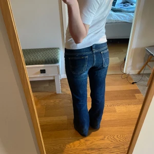 Blå Jeans - Jättesnygga lågmidjade bootcut jeans från lee. De är i ett bra skick! Har en liten slitning under knät men den syns inte när man har på sig dem. W28 L33. Upplagda, så de passar mig som är 160, men inte klippt av. Går lätt att ta ner!🩷 