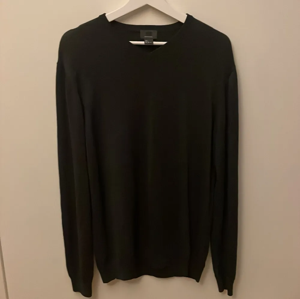 En mörkgrå merinoulls sweatshirt från HM i storlek L med V-ringad krage, inga defekter finns! Den är i väldigt bra skick!. Stickat.