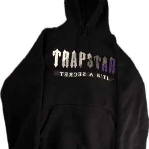Svart Trapstar hoodie - En svart Trapstar hoodie, storlek S, men passar M. Skick 9/10, nästintill ny. Föreslå ett pris du är villig att betala, kan tänka mig att gå ner en del i pris vid snabb affär. Skriv till mig vid minsta fundering eller om du vill ha fler bilder. Äkta.