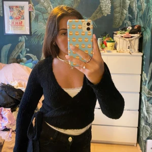 Svart omlottkofta  - Så gullig svart omlottkofta!  Kort i magen med långa ärmar. Långa band man knyter till rosett på sidan. Så söt att ha över en långklänning i vår/sommar! Har en likadan som är vit i flödet, kanske syns bättre där! 