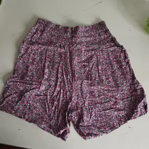 Högmidjade shorts med blommigt mönster från Monki. Tvättas i 30C°. 100% Viskos. Midjemått; 66 cm. Innerbensmått; 12 cm. Har rymliga fickor. Resår i ryggen.  Bra skick.