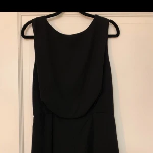 Jumpsuit - Svart shorts jumpsuit med spetsdetalj i ryggen. 