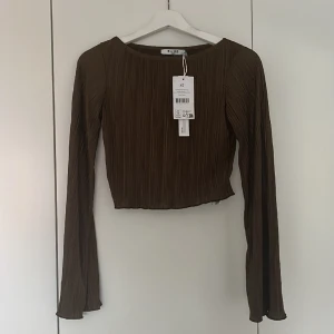 Blus från Nakd - Superfin croppad blus med vida ärmar från Nakd. Plagget är oanvänt och har lapparna kvar. Skimrigt och strukturerat material. 🤎