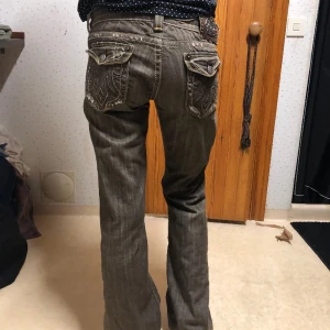 Vintage jeans - Lågmidjade, bootcut, passar de som har storlek M. Sitter baggy på mig som oftast har storlek 36/38 på jeans ⚠️Slitna nere vid hälarna⚠️ bild fanns inte plats så hör av er för att få bild!  Färgen på jeansen skiftar i brun/grå