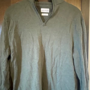 Grå tröja med dragkedja från Banana Republic - Säljer en snygg och bekväm grå tröja från These glory days. Tröjan har en dragkedja vid halsen och är perfekt för både vardag och lite finare tillfällen. Den är långärmad och gjord i ett mjukt material som håller dig varm under kyligare dagar. Passar perfekt till höst och vinter!