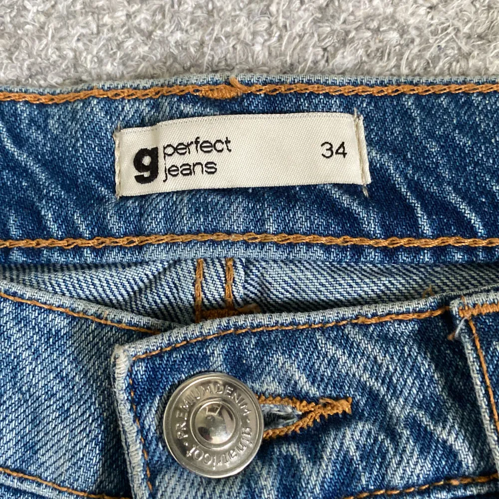 Säljer ett par snygga blå jeans från Gina Tricot i storlek 34. De är i en klassisk blå färg och har en straight fit men åt det mer wide leg hållet. Jeansen har en knapp och dragkedja framtill samt fem fickor. Perfekta för vardagsbruk och kan matchas med det mesta i garderoben. De är i mycket bra skick och redo för en ny ägare!. Jeans & Byxor.