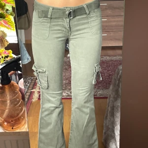 Lowrised boot cut cargo byxor  - Säljer dessa snygga cargo byxorna med boot cut form och tillhörande bälte 🤩 De är en aningens slitna längst ner men annars i bra skick ! Aldrig använda. Köptes på secondhand❤️ Säljer de för att de är alldeles för små för mig🫶🏼Kontakta mig vid intresse!