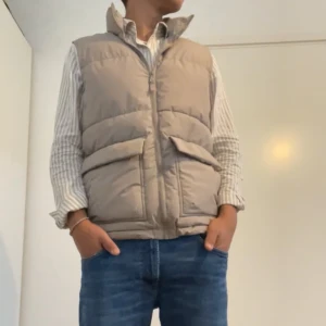Beige quiltad dunväst - Säljer en snygg beige quiltad dunväst. Västen har en dragkedja framtill och två stora fickor med lock. Perfekt för höst och vår när du vill hålla dig varm.. Passar bra över en tröja eller skjorta. Västen är i nyskick och knappt använd. Hör av er vid frågor 😁
