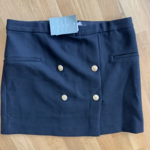 Kort kostymkjol - Svart kostymkjol med gulddetaljer. Helt oanvänd med prislapp kvar. Köpt på HM. Lite liten i storleken 